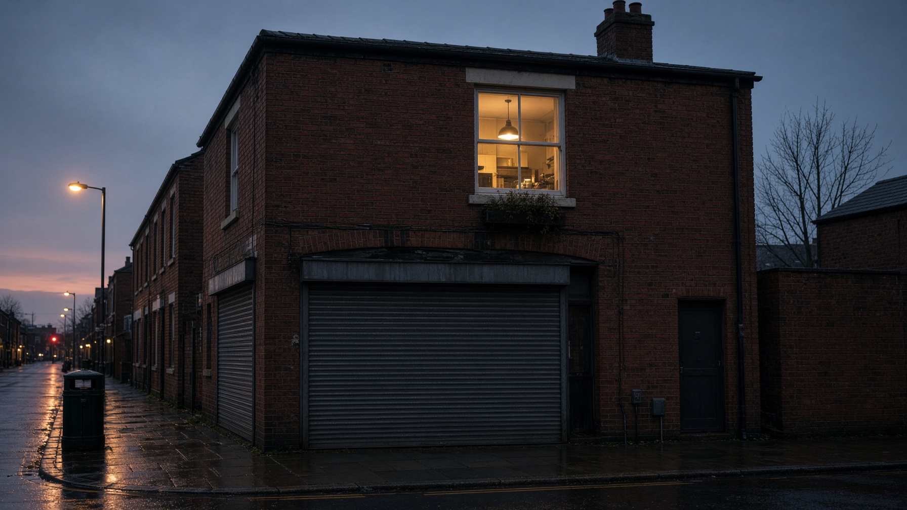 Corner shop with a lit flat above at dusk